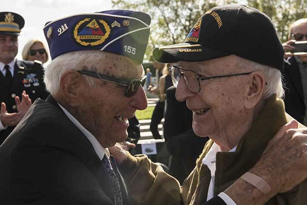 Two veterans smiling, greeting each other and looking in each other's eyes.