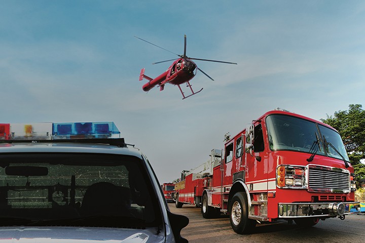 Helicopter flying over firetruck and police car