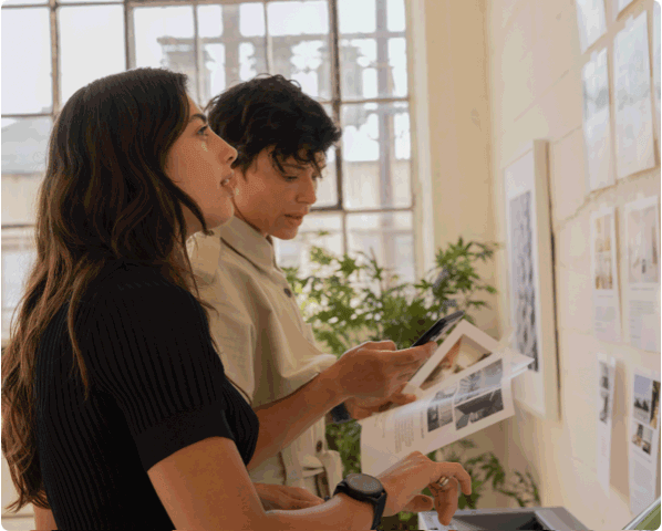 two women looking at papers on wall