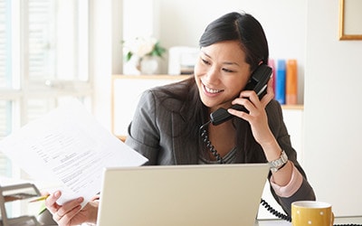 Businesswoman at office desk using Fios digital voice service.