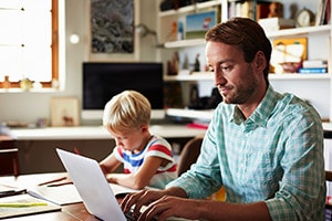 Father and son both at table working.