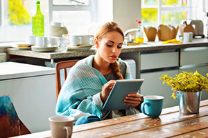 Woman having coffee in the morning using her tablet
