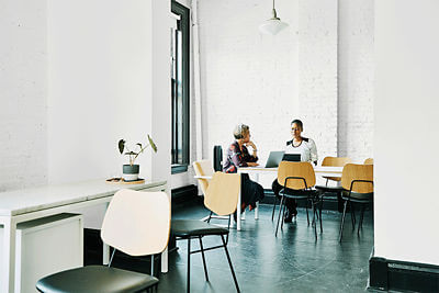 Photo of open floor plan office setting with people using technology.